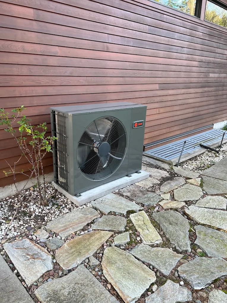 Central air conditioning condenser being installed beside a Burnaby home