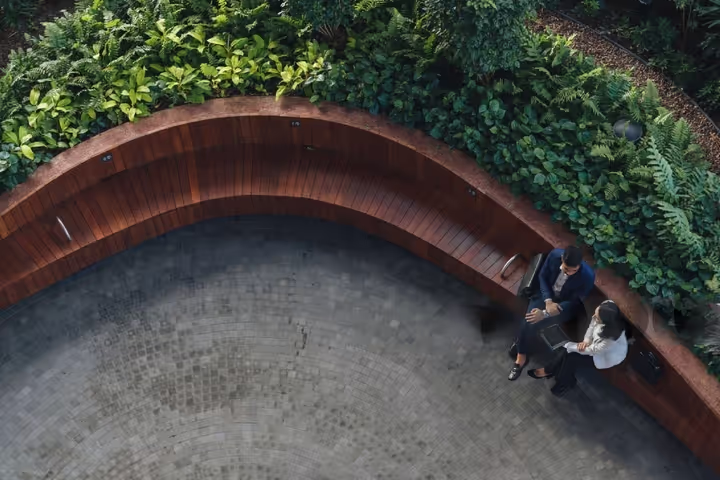 Birds eye view of two people sitting down on a bench in a communal space