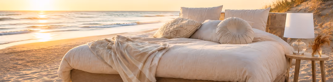 Luxe boxspring op het strand tijdens zonsondergang als symbool voor investeren in beter slapen met vakantiegeld.