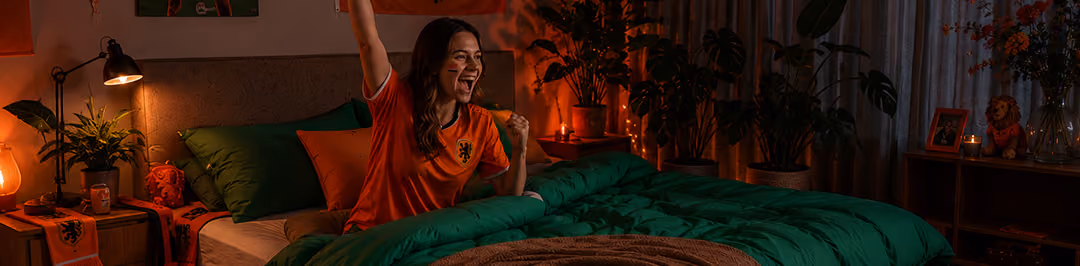 mevrouw zit in haar oranje tenue in bed en juicht