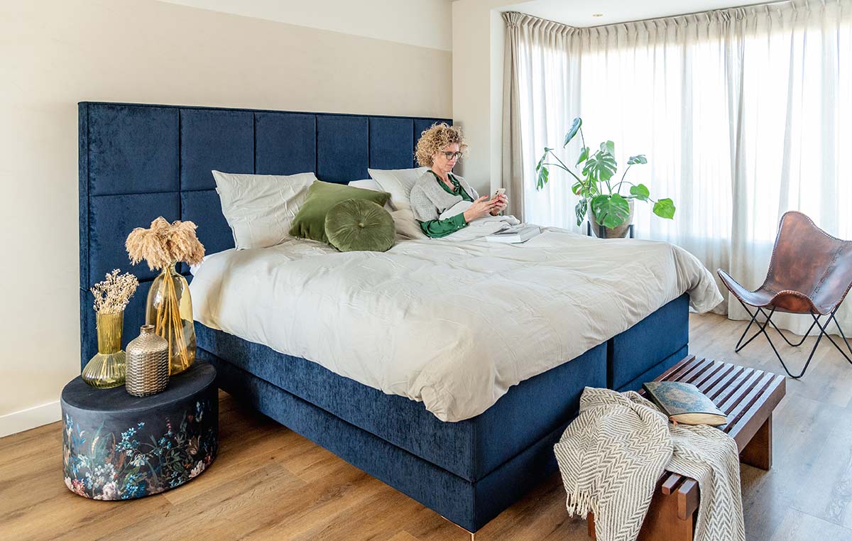 Mevrouw zit in blauwe Softline boxspring boek te lezen