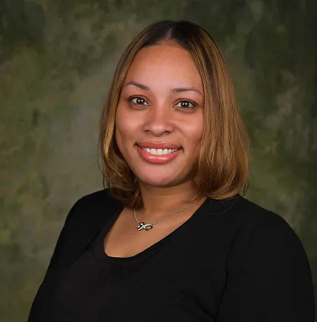  A professional portrait of a woman smiling in front of a studio-style green mottled background.