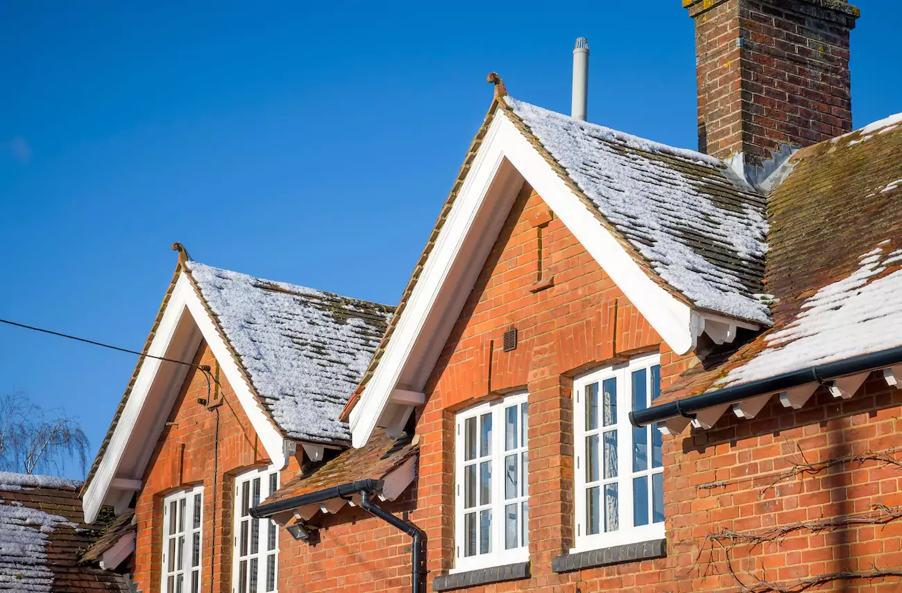Victorian UK terraced house on sunny winter day with ice on roof.