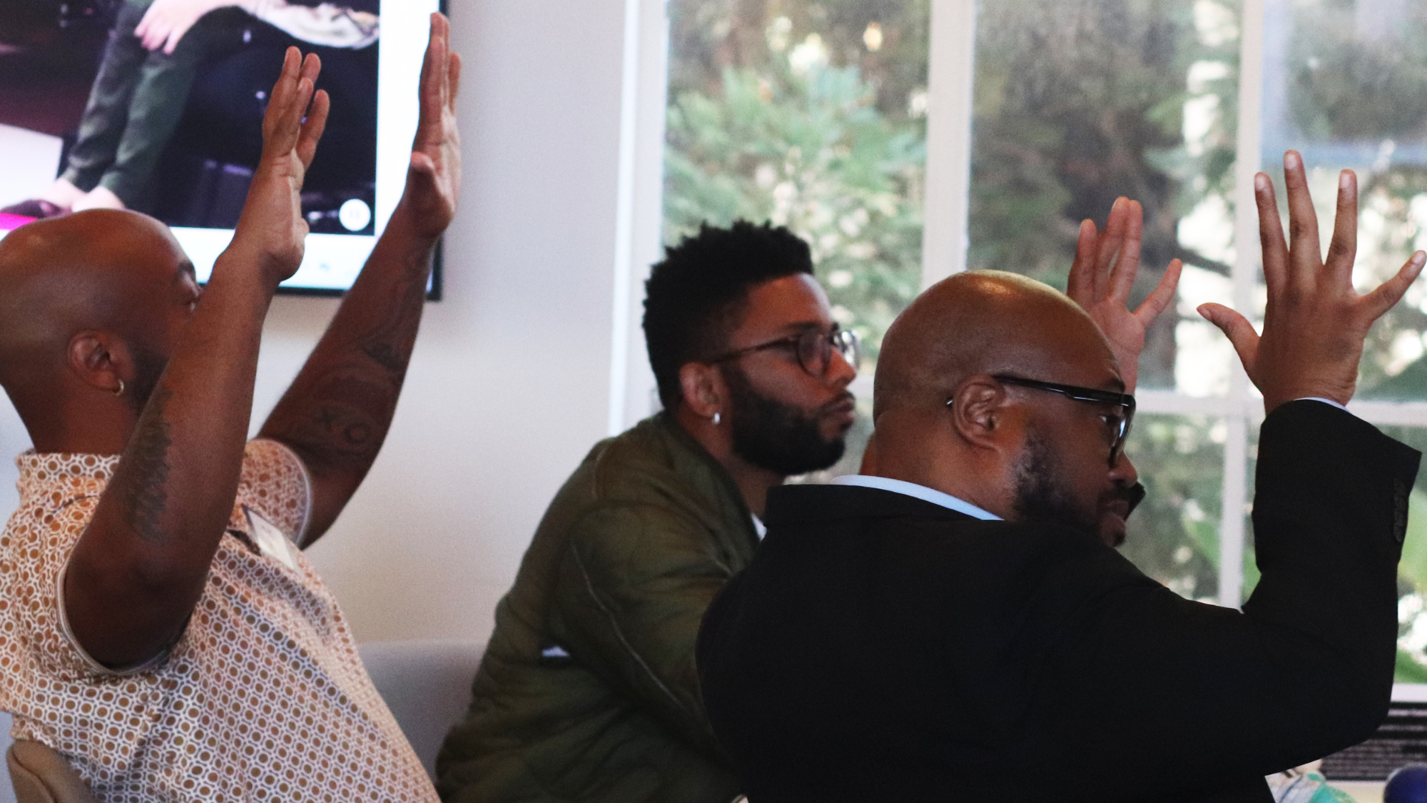 Three Black, masculine presenting Making Space community members applaud in ASL. 
