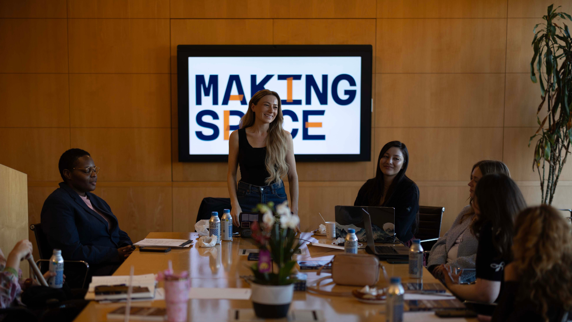 Keely speaking to a conference room of Disabled jobseekers with a screen projecting the Making Space logo behind her.