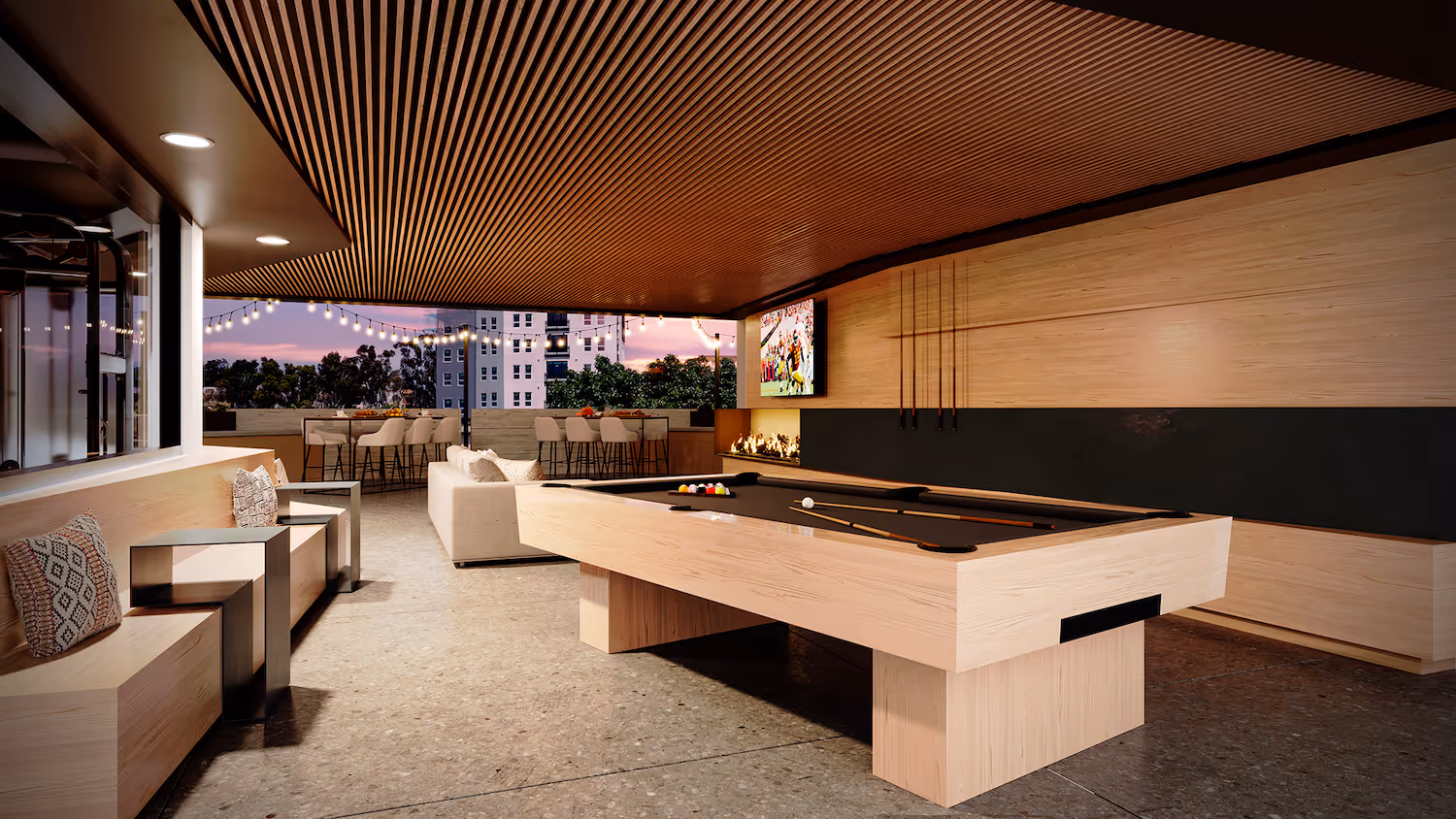 Rooftop gaming lounge with a billiards table, TV, and modern seating, providing evening entertainment for residents at Tessera in Los Angeles, CA.