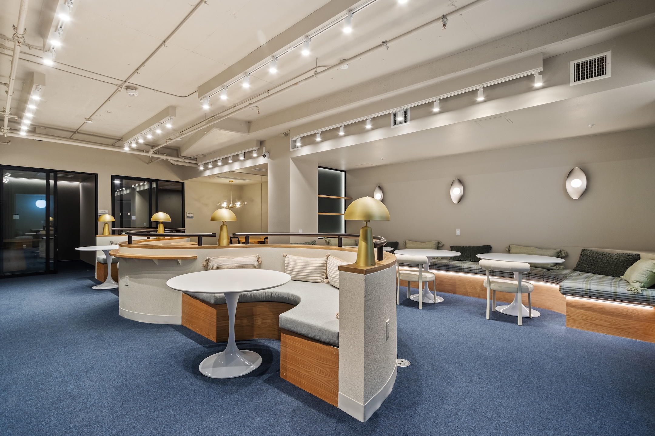 Modern co-working lounge with individual desks, communal seating, and computers, providing a productive environment for residents at Tessera in Los Angeles, CA.