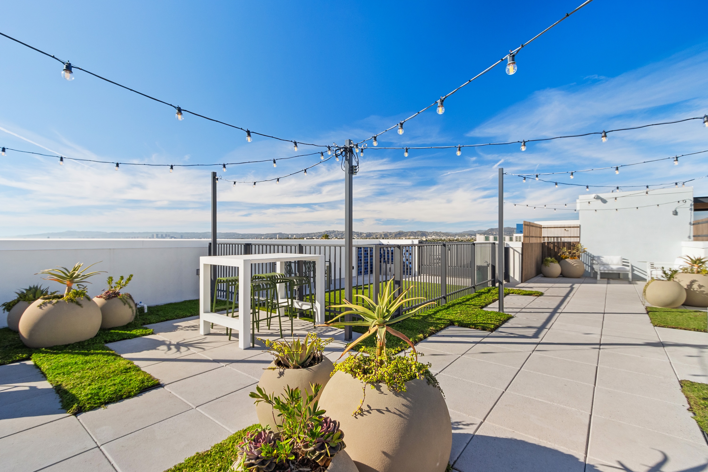 Rooftop dining space with a large communal table, bar, and outdoor kitchen, offering residents a social hub at Tessera in Los Angeles, CA.