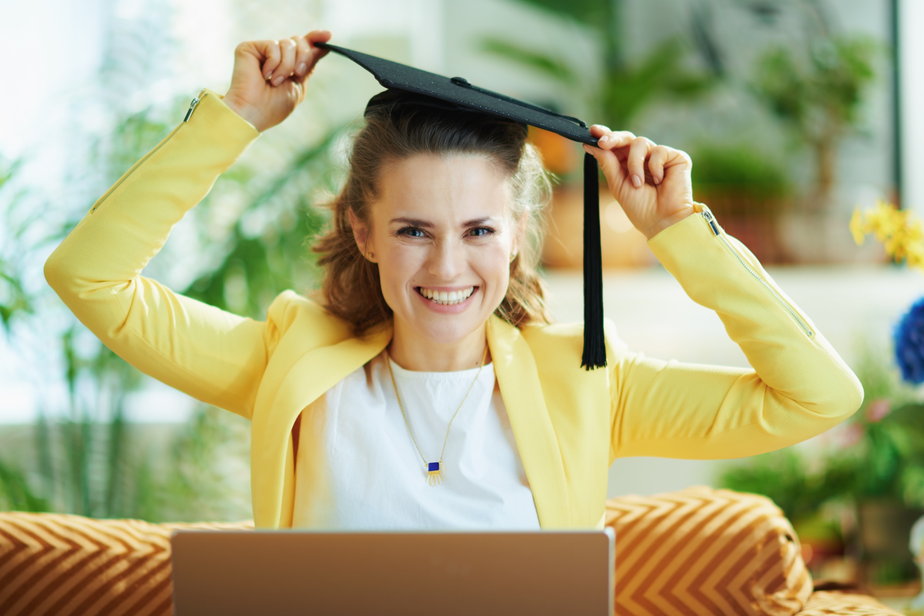 A smiling resident celebrating graduation with a cap and laptop in Los Angeles, CA.