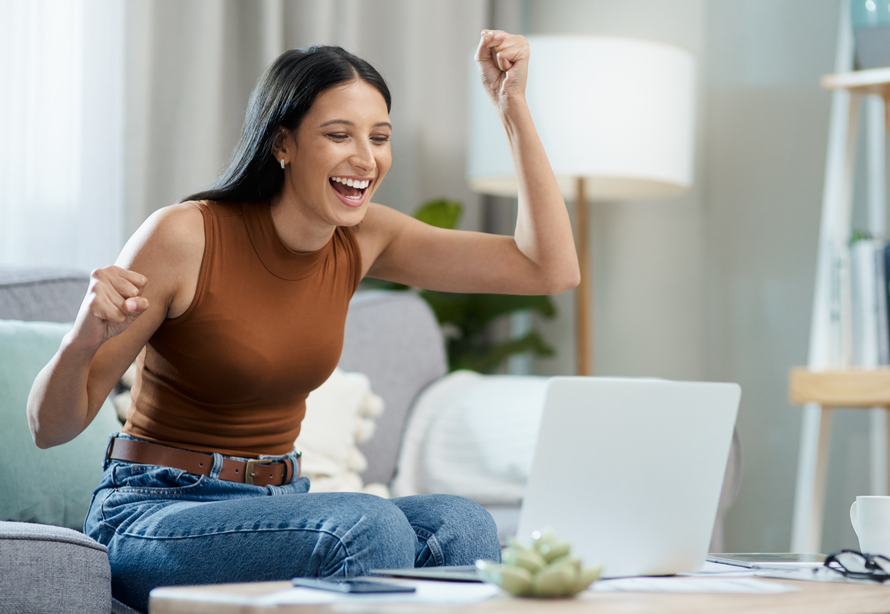 Resident celebrating while looking at a laptop inside a living room at Tessera in Los Angeles, CA