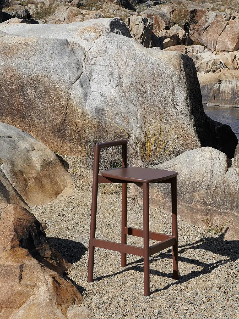 Fable outside black chair on wet dock beside lake with scattered ice cubes on seat and ground at dawn.