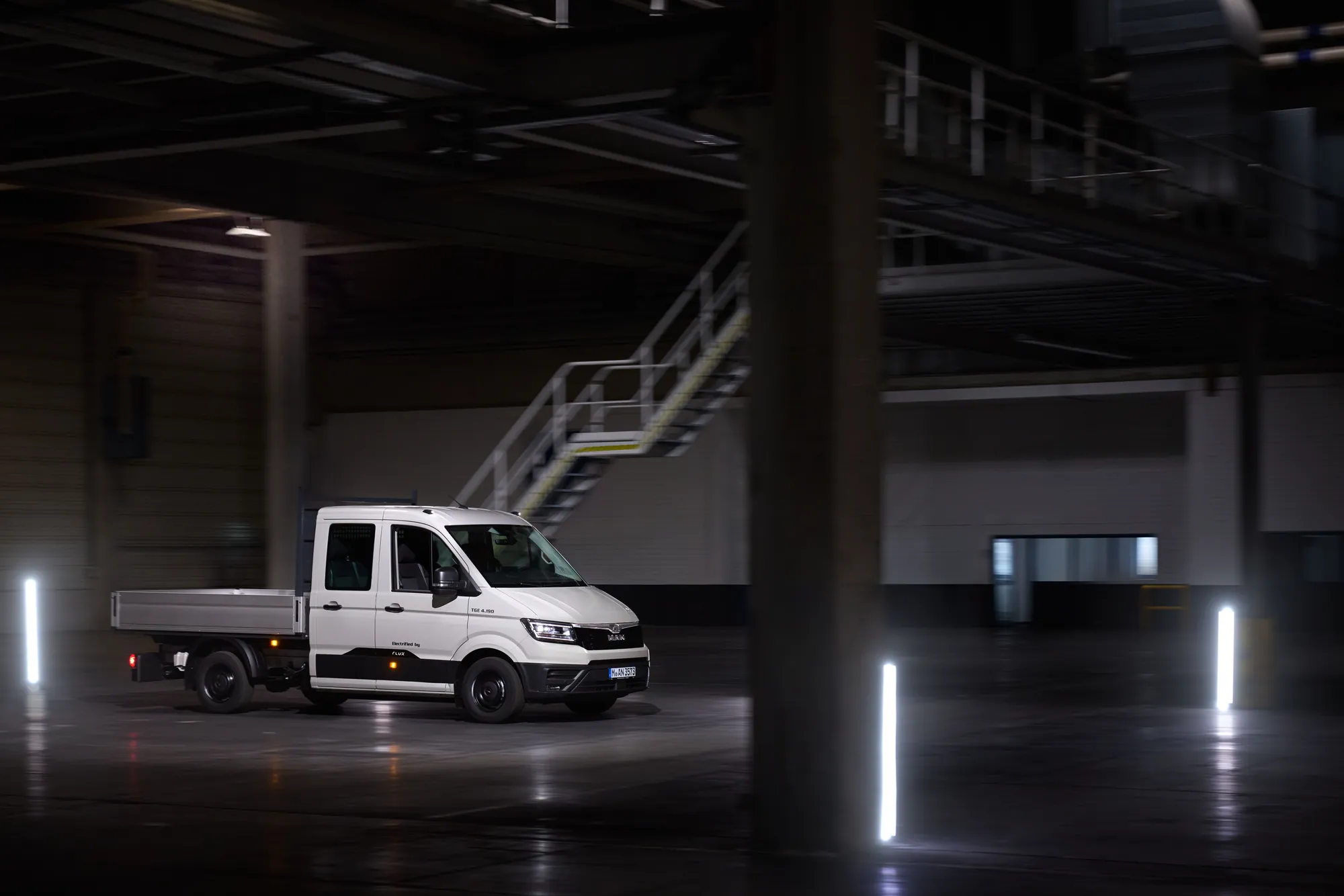 MAN TGE electrified by Flux als Doppelkabine 4,0 t einzelbereift mit Pritsche, Seitenansicht in einer Halle