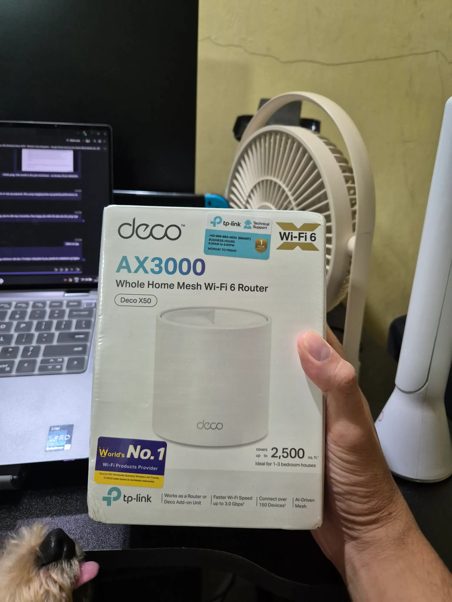A photo of me holding abox of Deco AX3000 X50 home mesh wifi 6 router with my dog's nose showing on the bottom left
