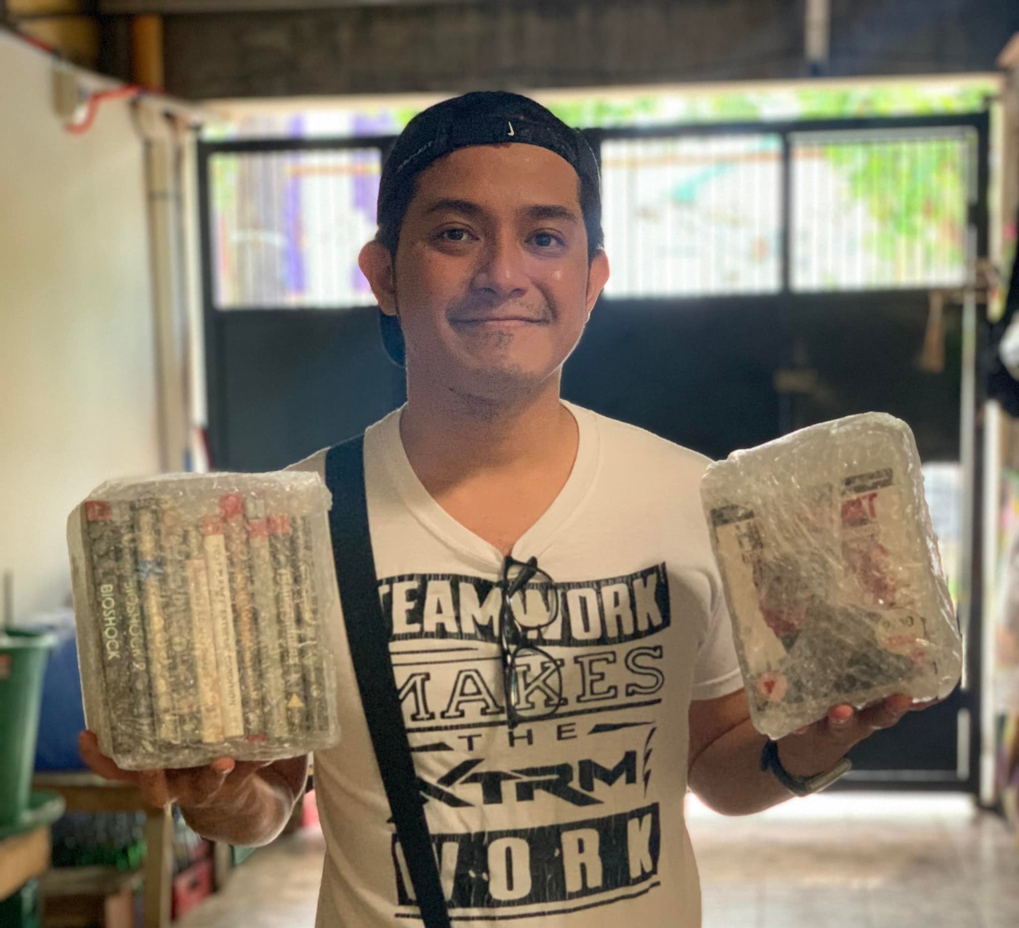 A photo on me on a white shirt and cap holding sealed PlayStation 3 games