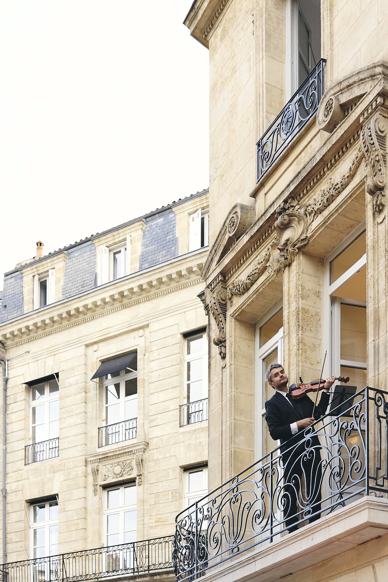 Violoniste au balcon de l’immeuble en pierre de Maison Espaces pendant l’inauguration