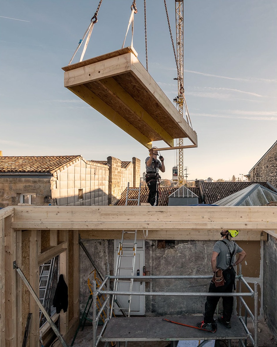 Grutage des modules préfabriqués en ossature bois de la surélévation HEDLO au-dessus des toits des Chartrons, Bordeaux