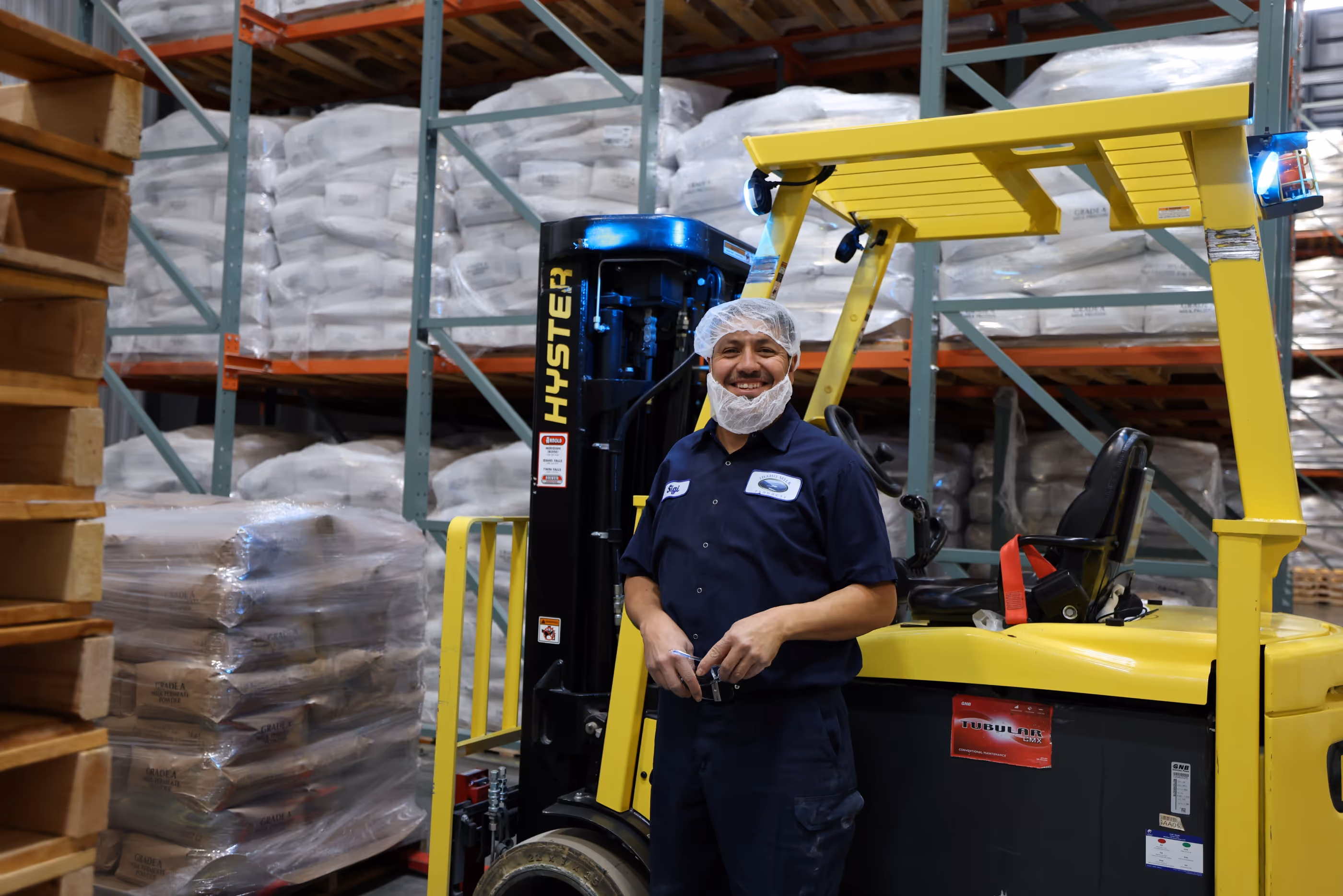An employee standing next to yellow hyster forklift
