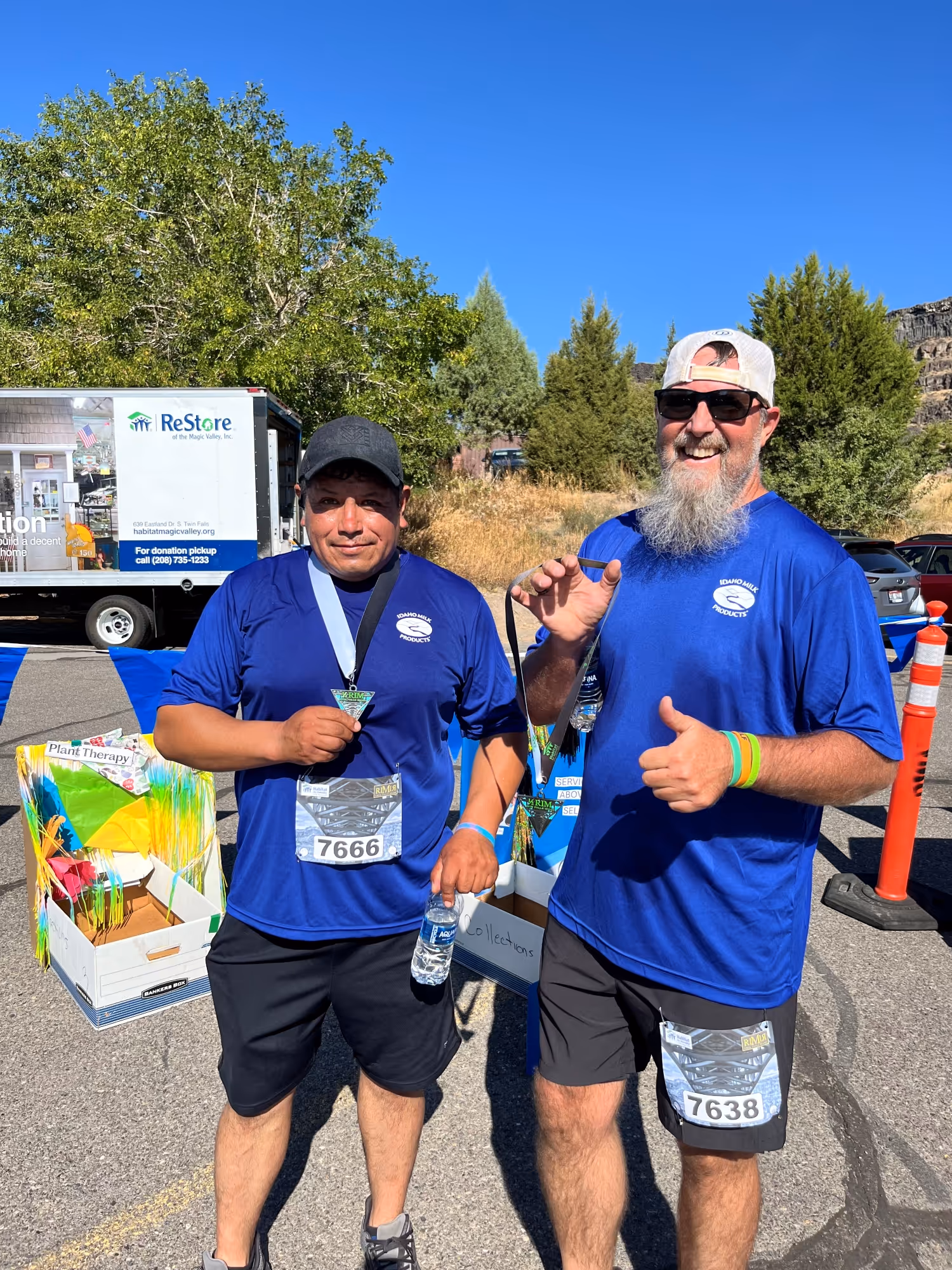 Two men, who are employees, hold up their medals they won during an event.