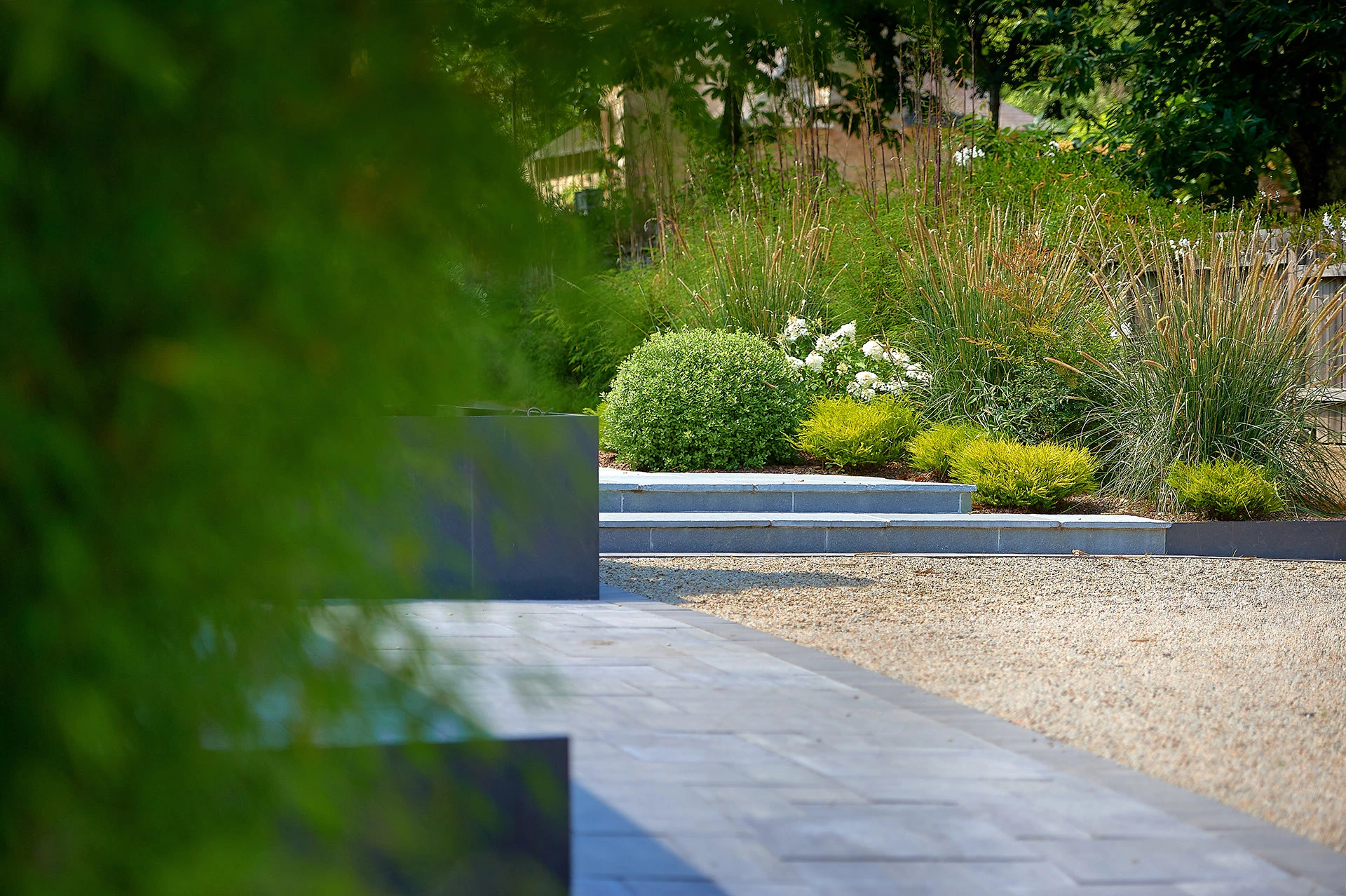 parking moderne en pavés et graviers beige conduisant à un escalier en pierres naturelles