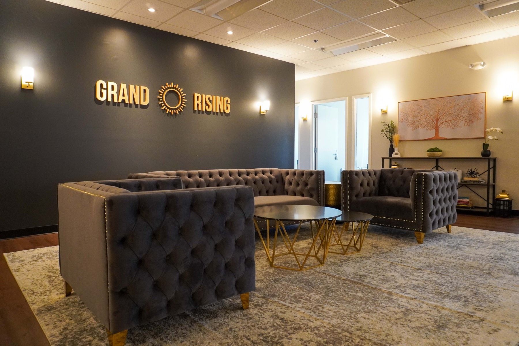 The calming, hospitality-style lounge at Grand Rising Behavioral Health with plush velvet seating and the Grand Rising sign on a dark accent wall
