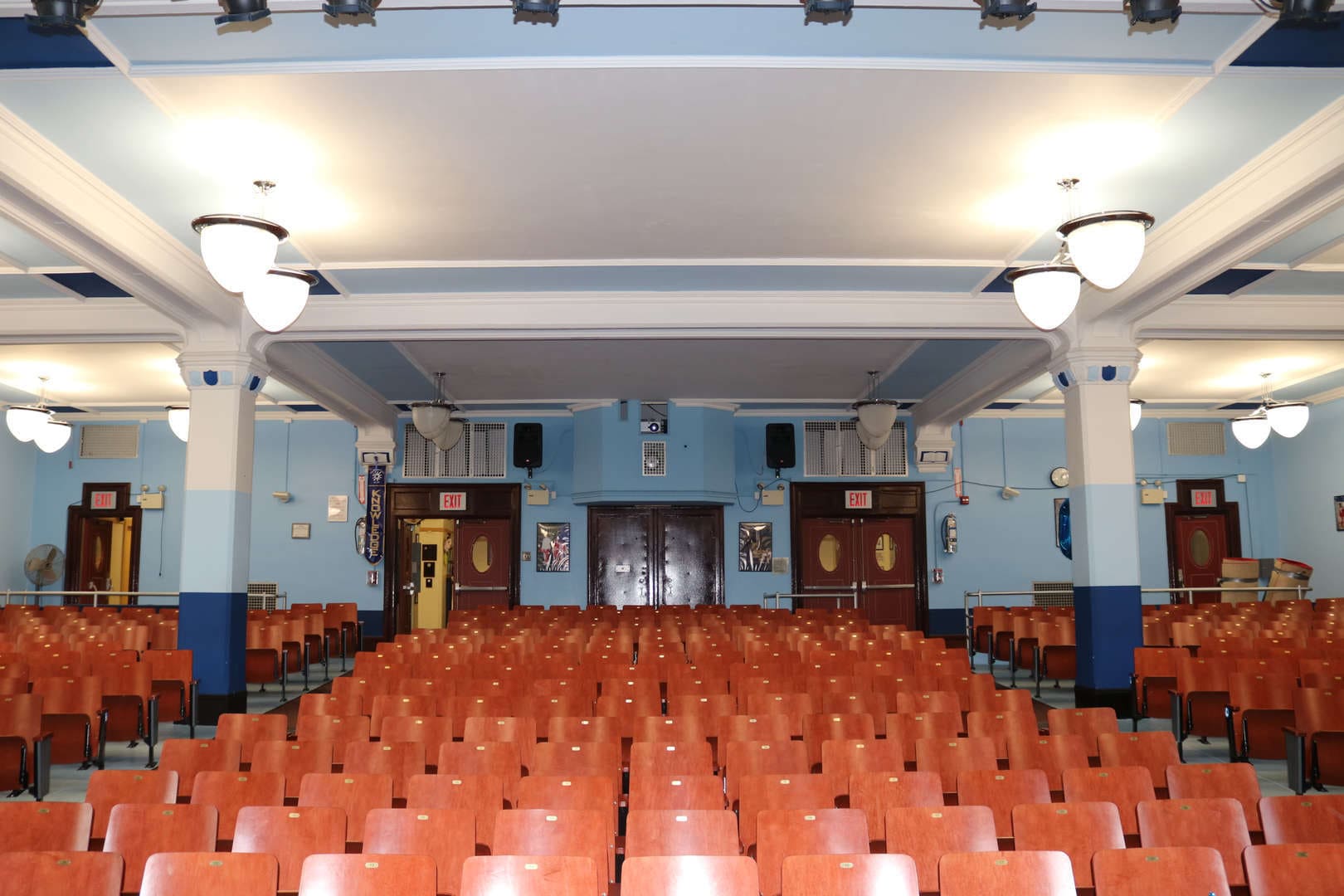 Empty school auditorium with rows of wooden seats and exit doors