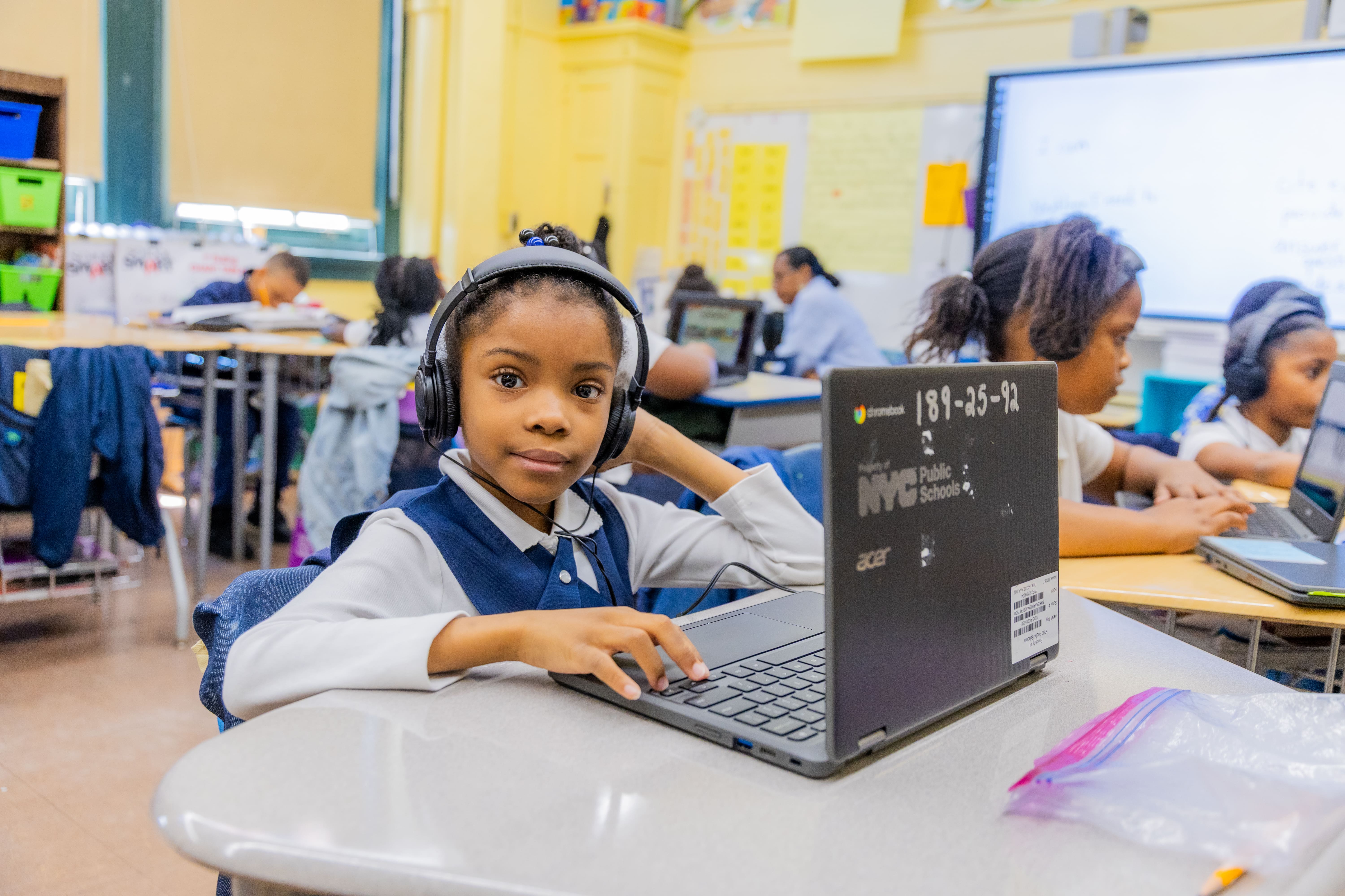 Student with headphones using an NYC Public Schools Chromebook in class