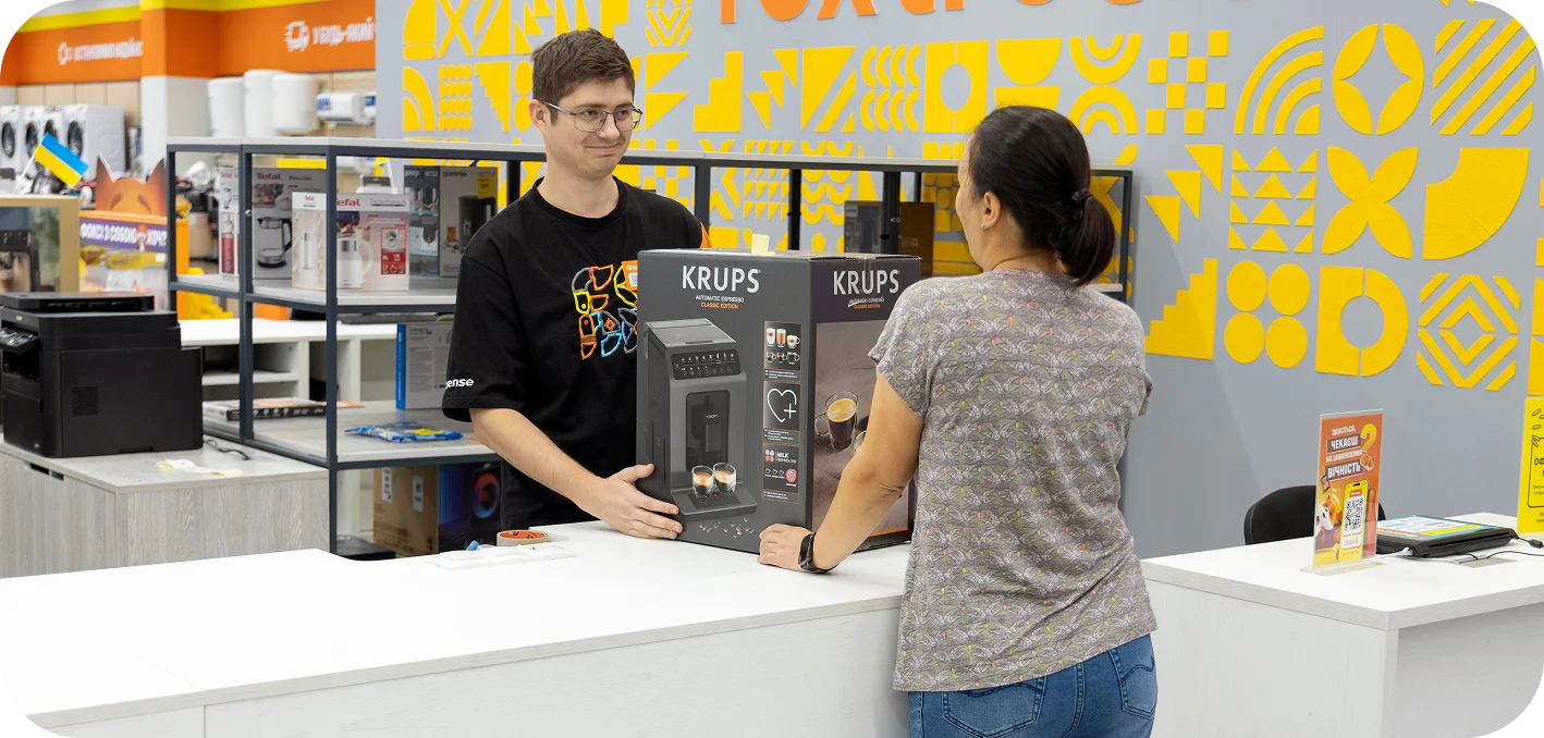 Продавець Foxtrot передає клієнтці кавомашину Krups у відділі техніки