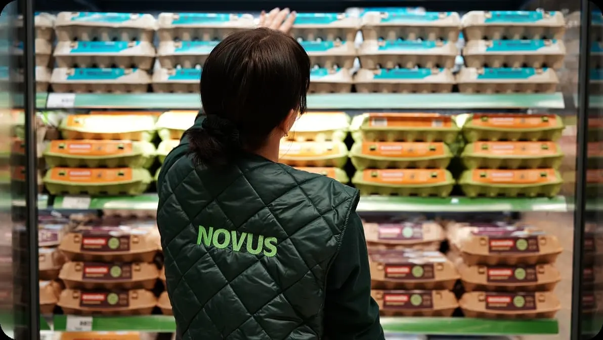 Працівниця NOVUS викладає товари власної торгової марки на полиці магазину