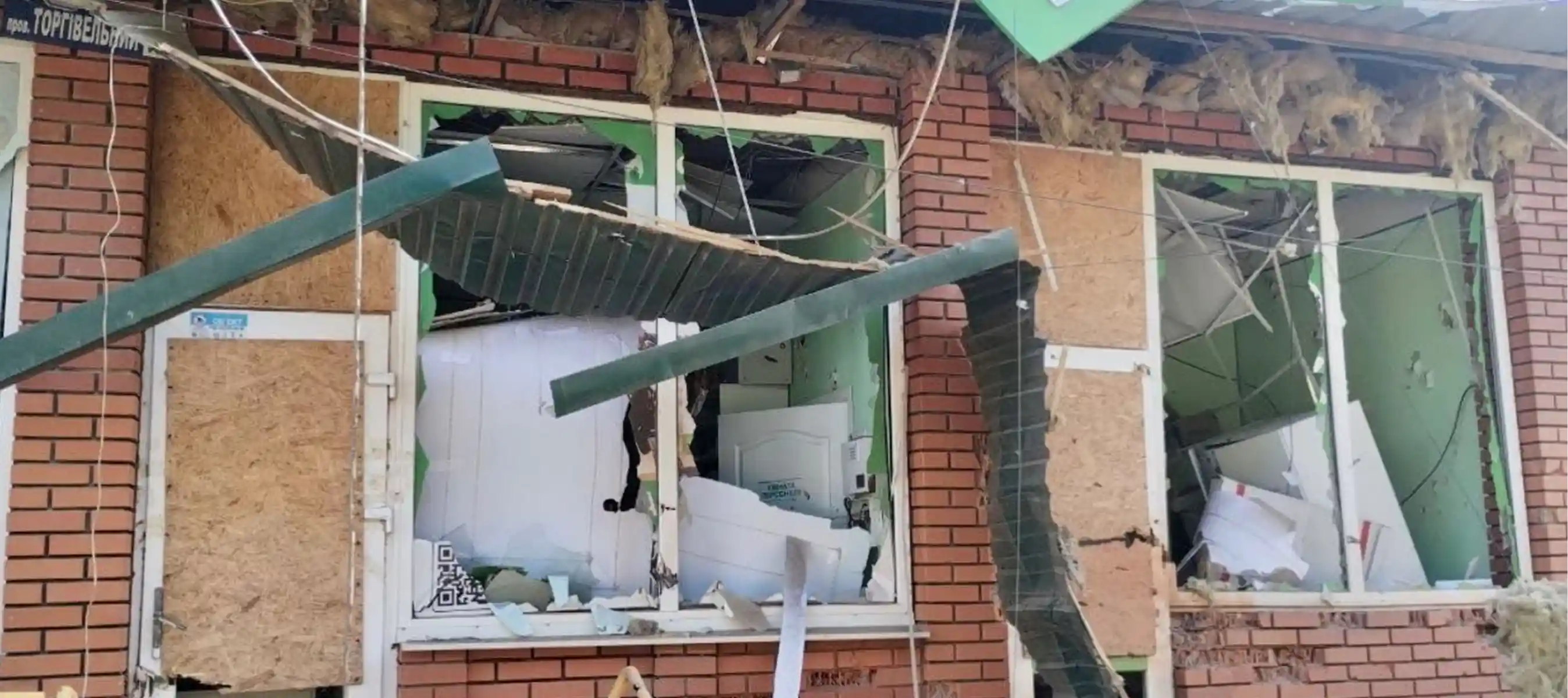 Пошкоджена будівля аптеки після обстрілу вибиті вікна та зруйнований фасад