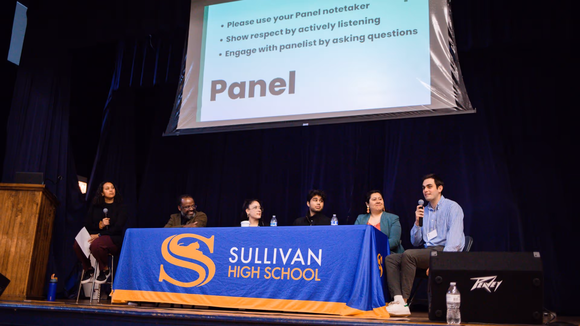 A group of people sitting at a table with a sign that says "Sullivan High School".