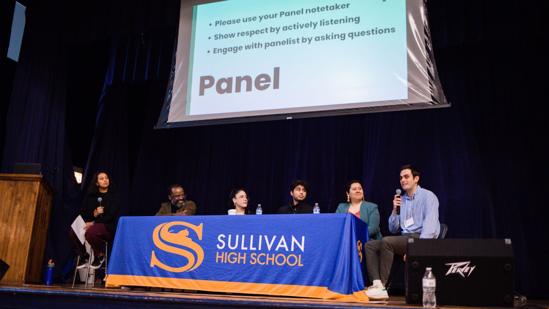 A group of people sitting at a table with a sign that says "Sullivan High School".
