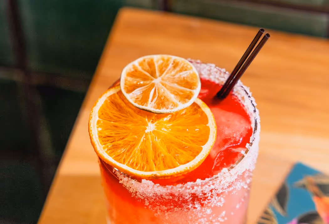 Red Margarita with orange slices and salt rim.