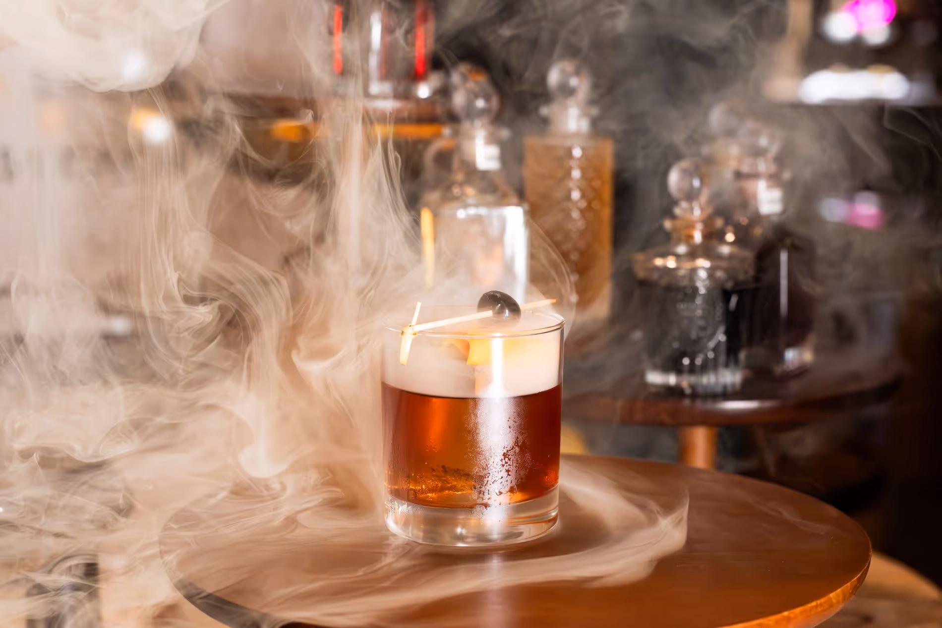 Old Fashioned cocktail with smoke and glass decanters in background