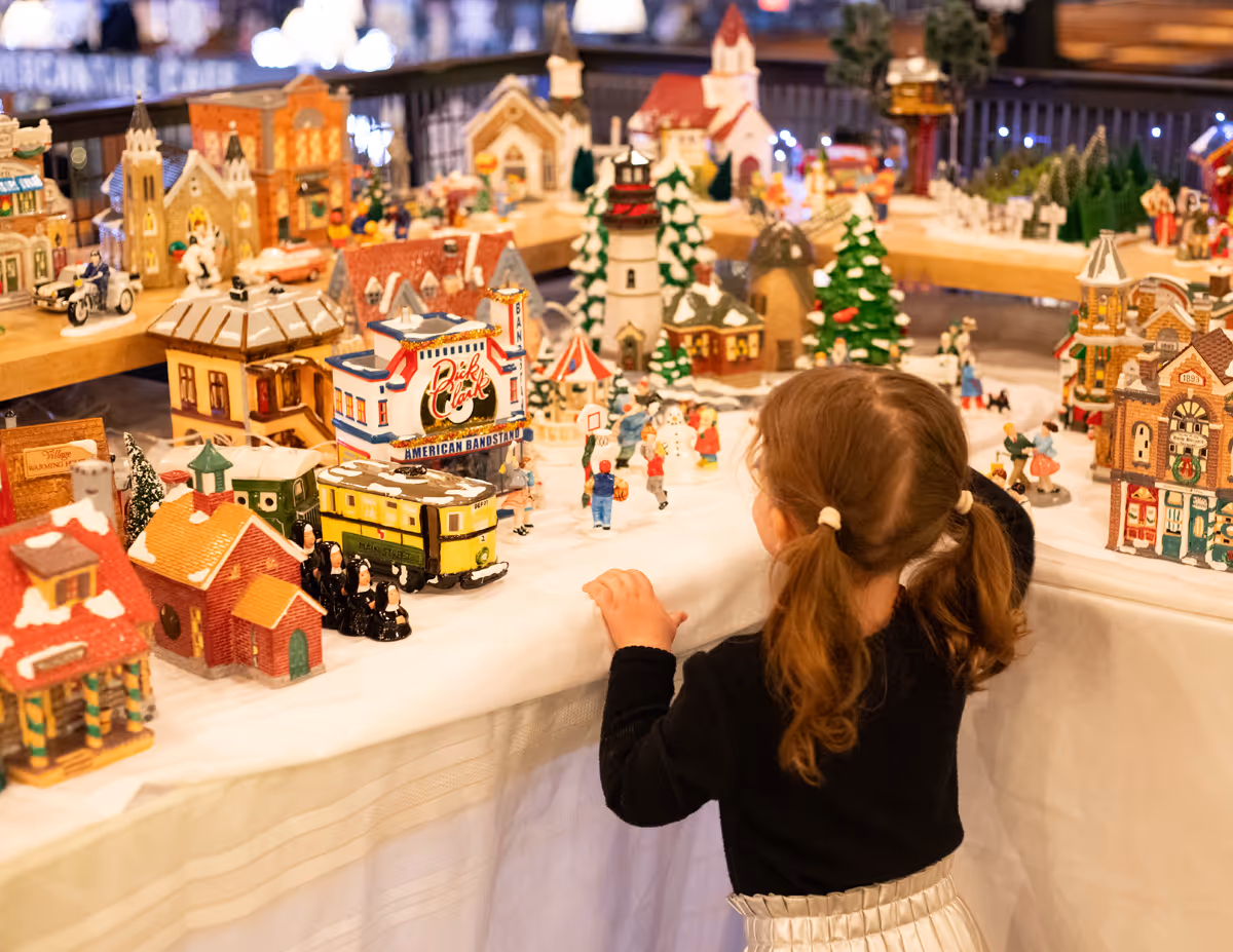 Young girl admiring a miniature  Christmas village