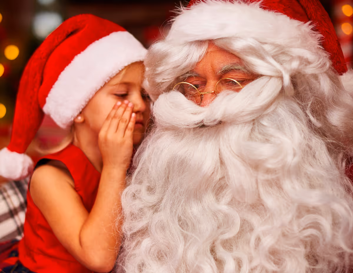 Young girl whispering in Santas ear