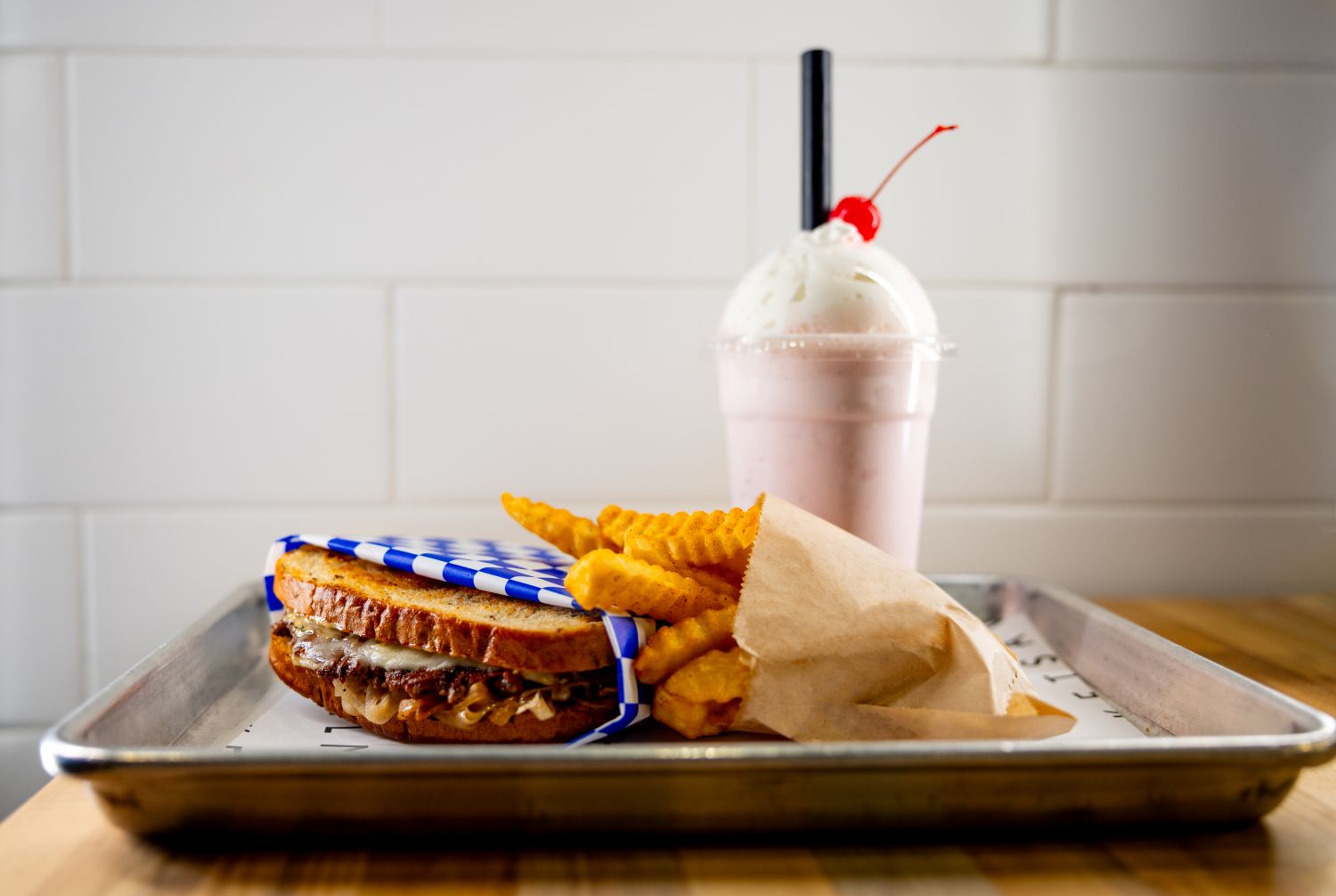 Patty melt on a tray with fries and a shake
