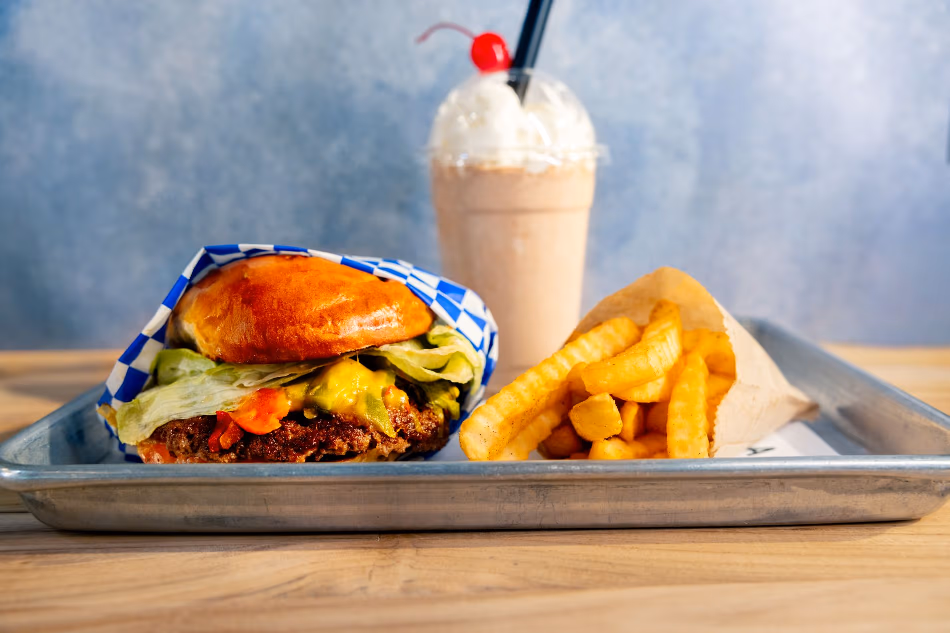 tray with a cheeseburger, fries and a chocolate shake