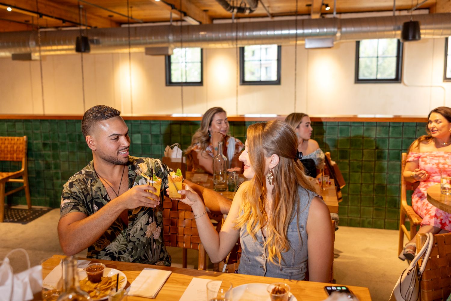 A mand and woman sitting next to each other in Flora holding up margaritas