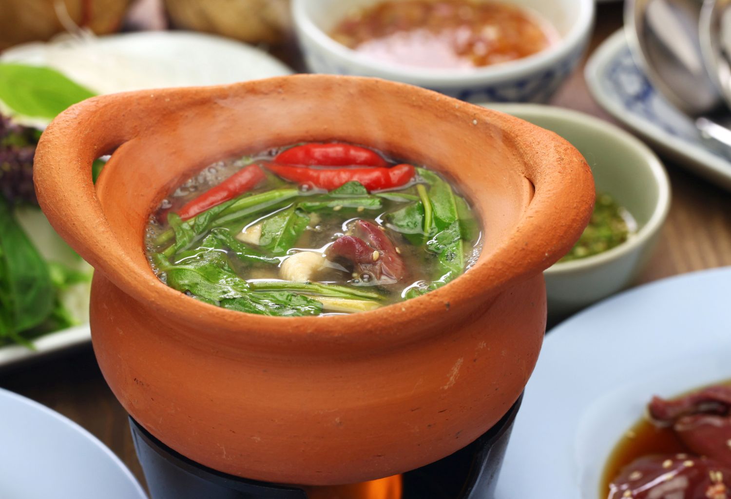 Clay pot with broth and vegetables