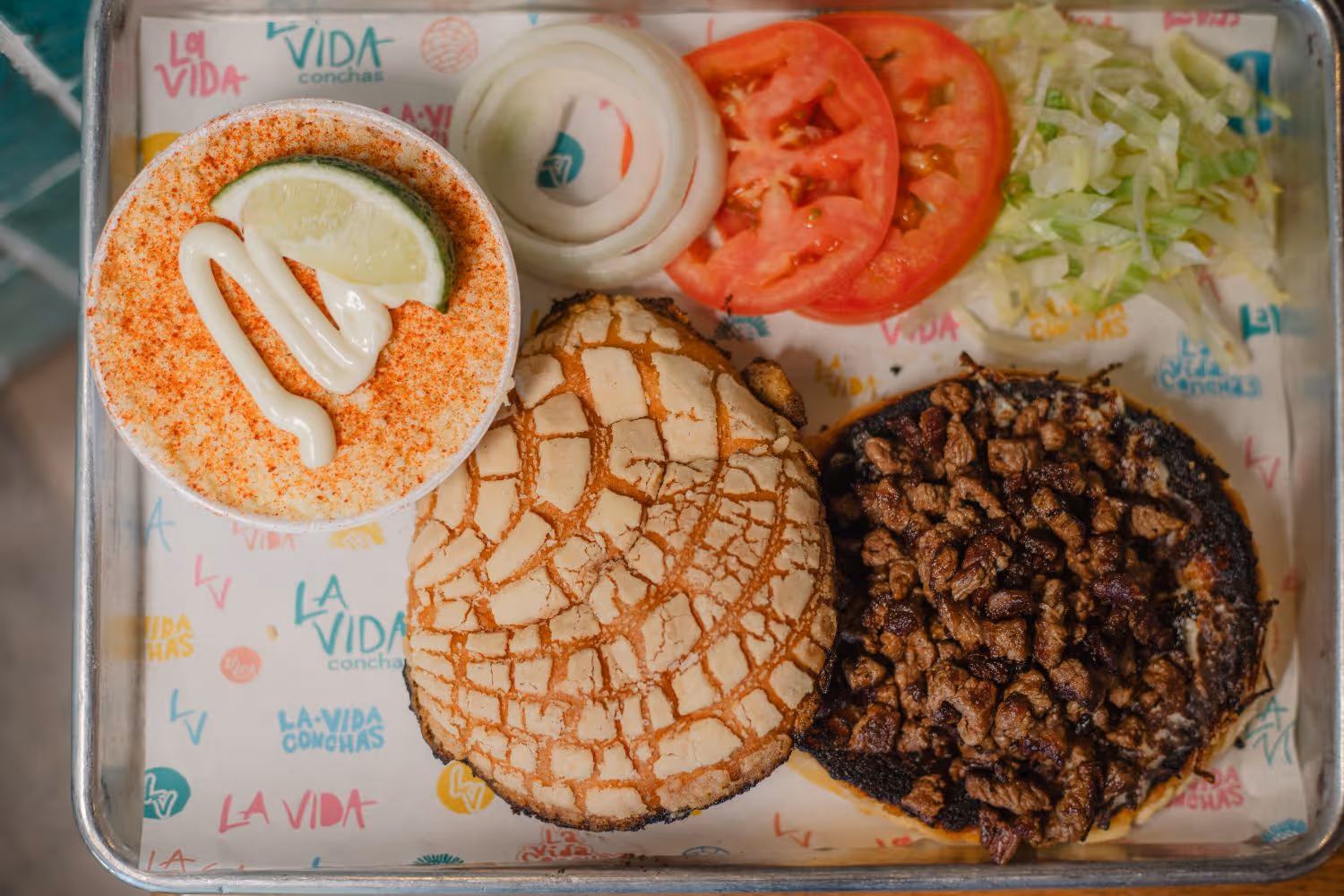 tray with a deconstructed concha sandwich with meat, lettuce, tomato and onion on a tray