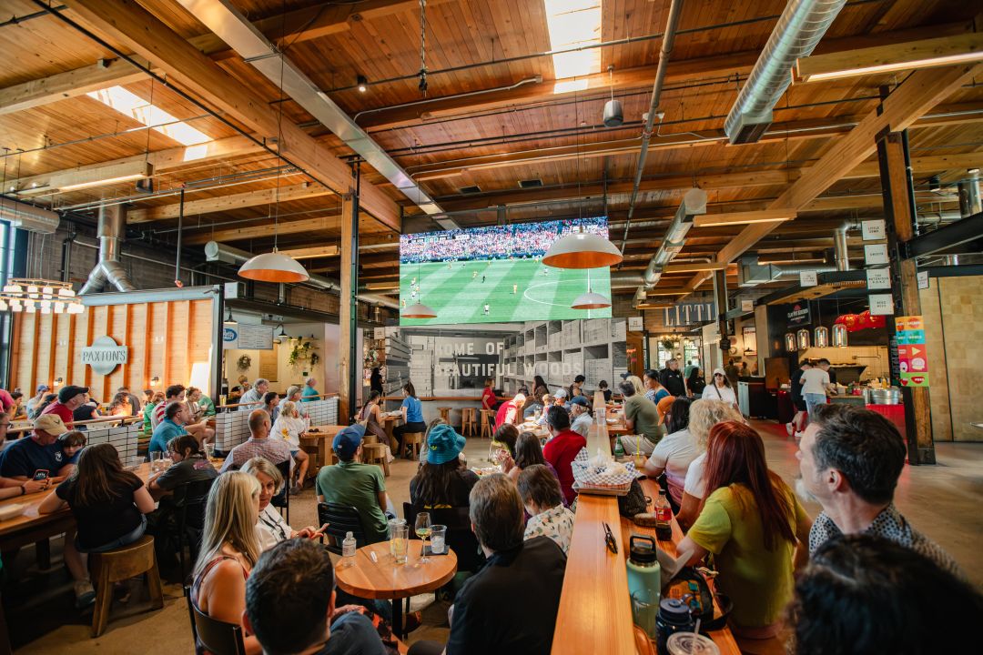 Group of people watching a soccer game in Sawmill Market.