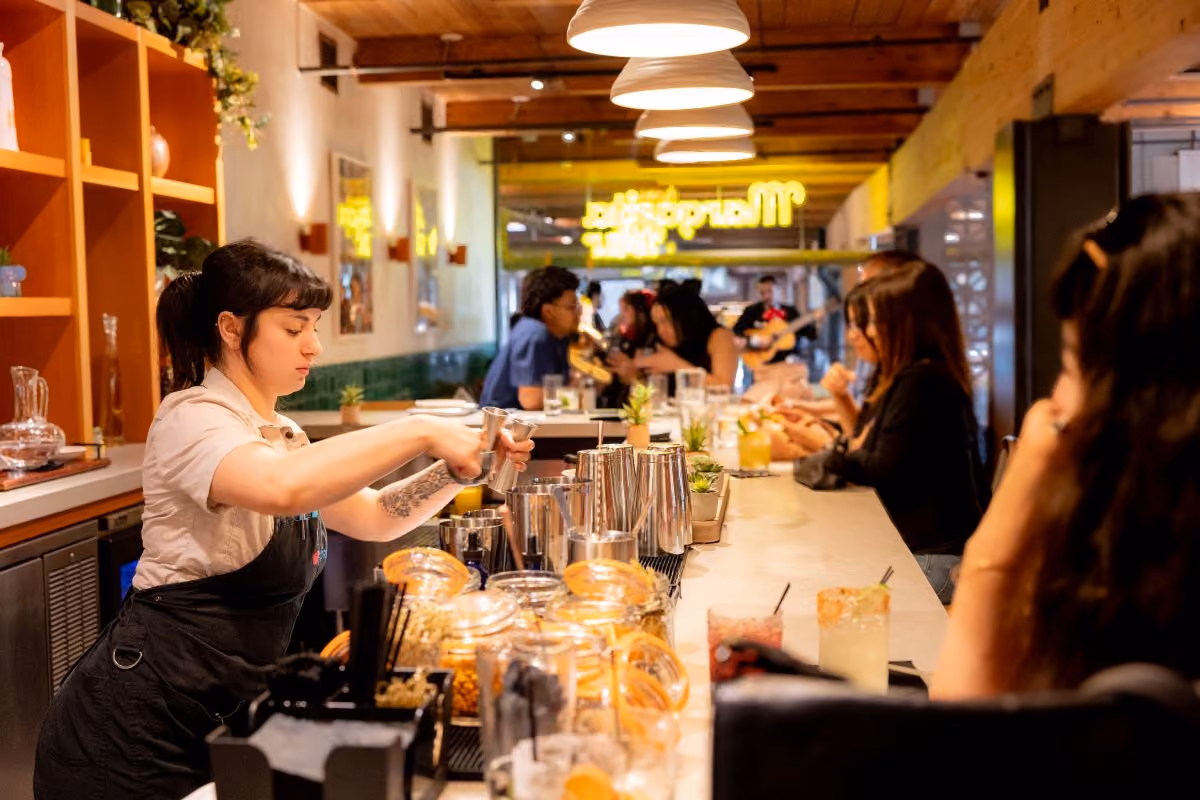 Bartender pouring drink, at Margarita Bar, with several guests sitting at bar