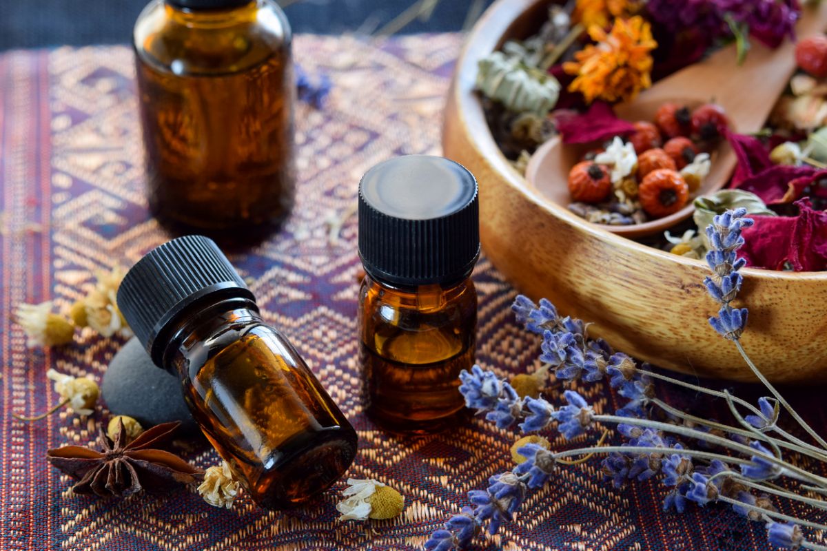 Small bottle for essential oils near bowl of scented flowers