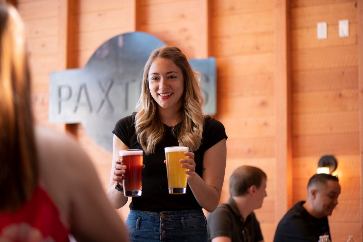 Woman filling a glass in Paxton's with cocktail on tap