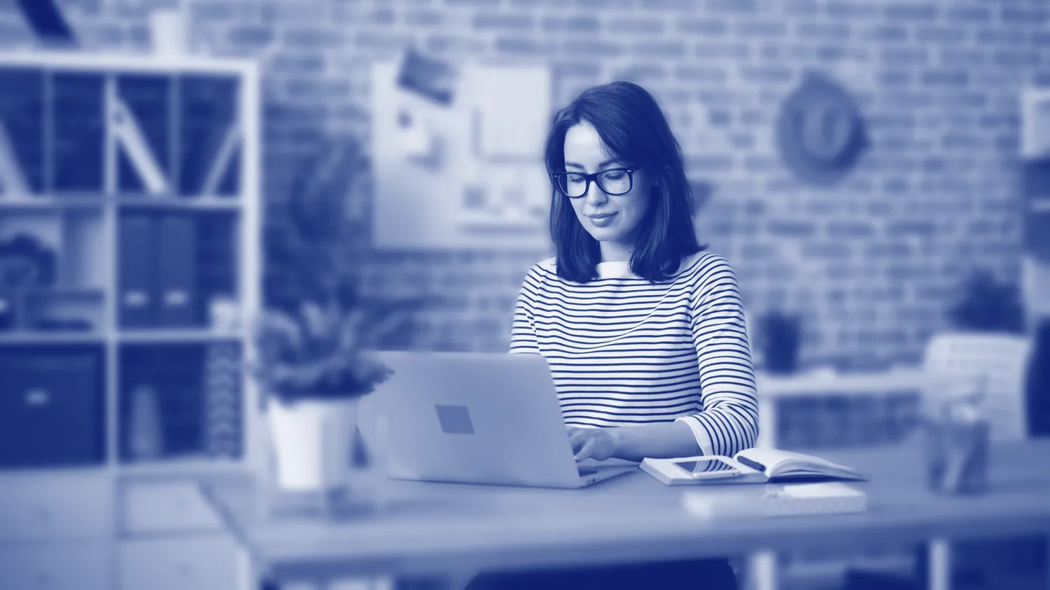 Woman sitting at a desk using a laptop.