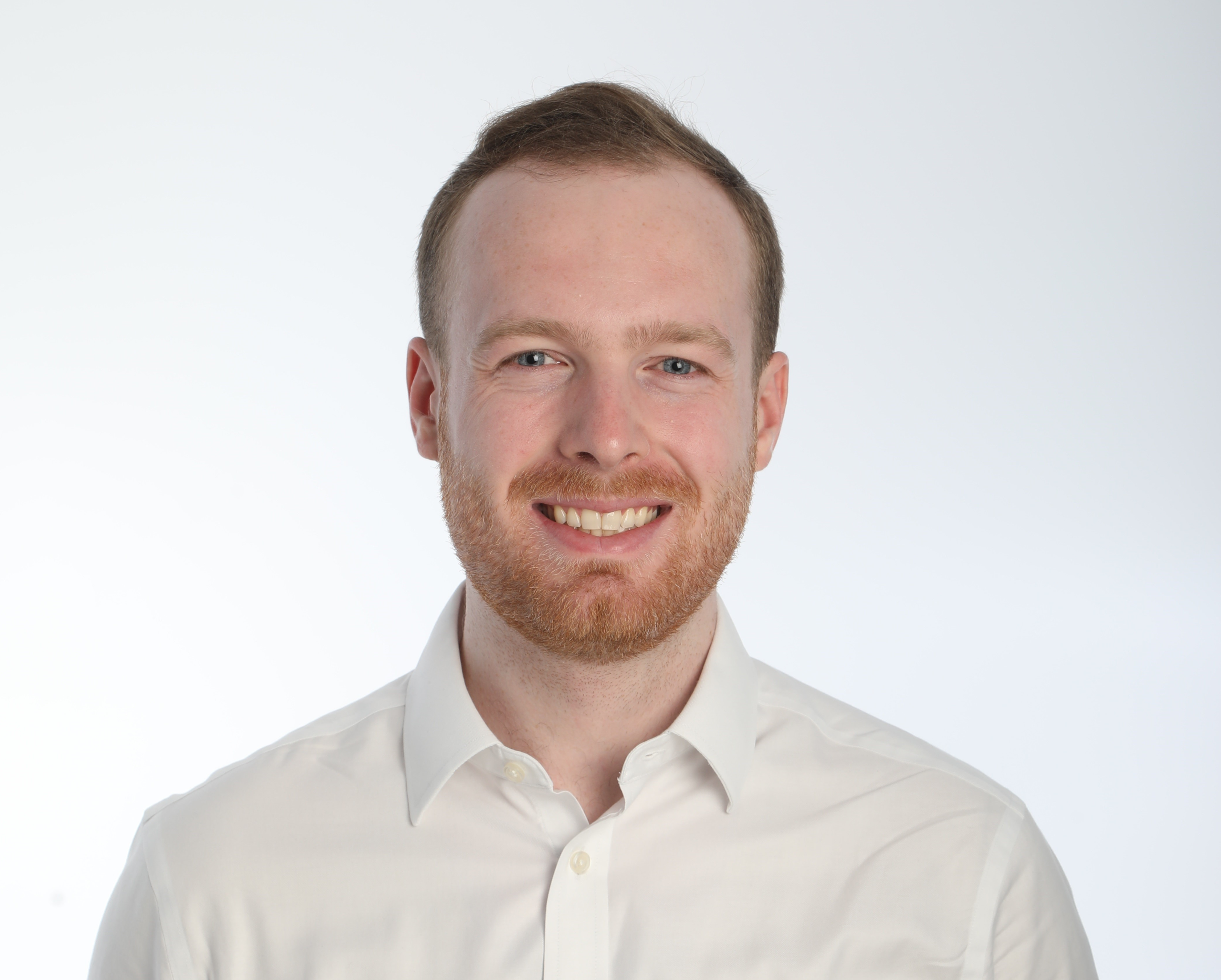 Photo of Jack;Photo of a smiling young man in a white shirt. He has thin hair, and a soft beard. The background is white.