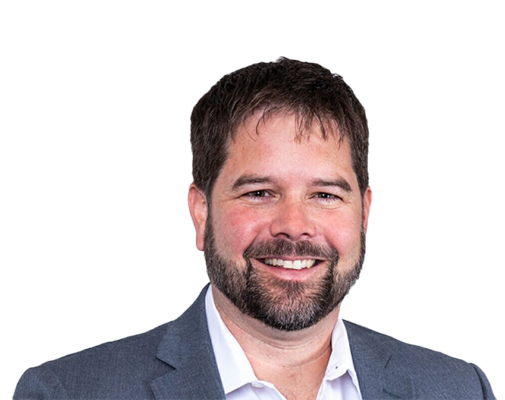 Photo of Chris; Professional headshot of a smiling man with short brown hair and a trimmed beard, wearing a grey suit blazer over an open-collar white shirt against a plain light gray background.