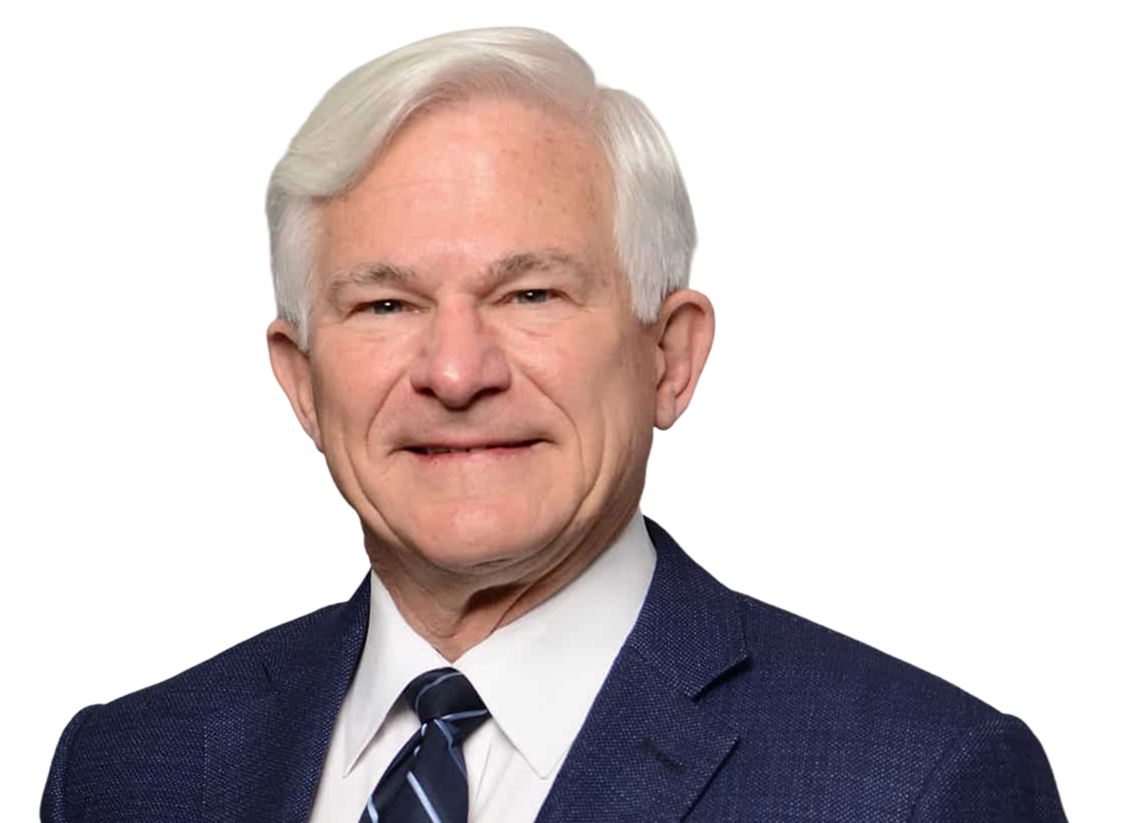 Photo of Larry Hilsheimer; Professional headshot of a smiling older man with short white hair, wearing a navy blue suit jacket, white collared shirt, and a dark blue striped tie against a plain light gray background.