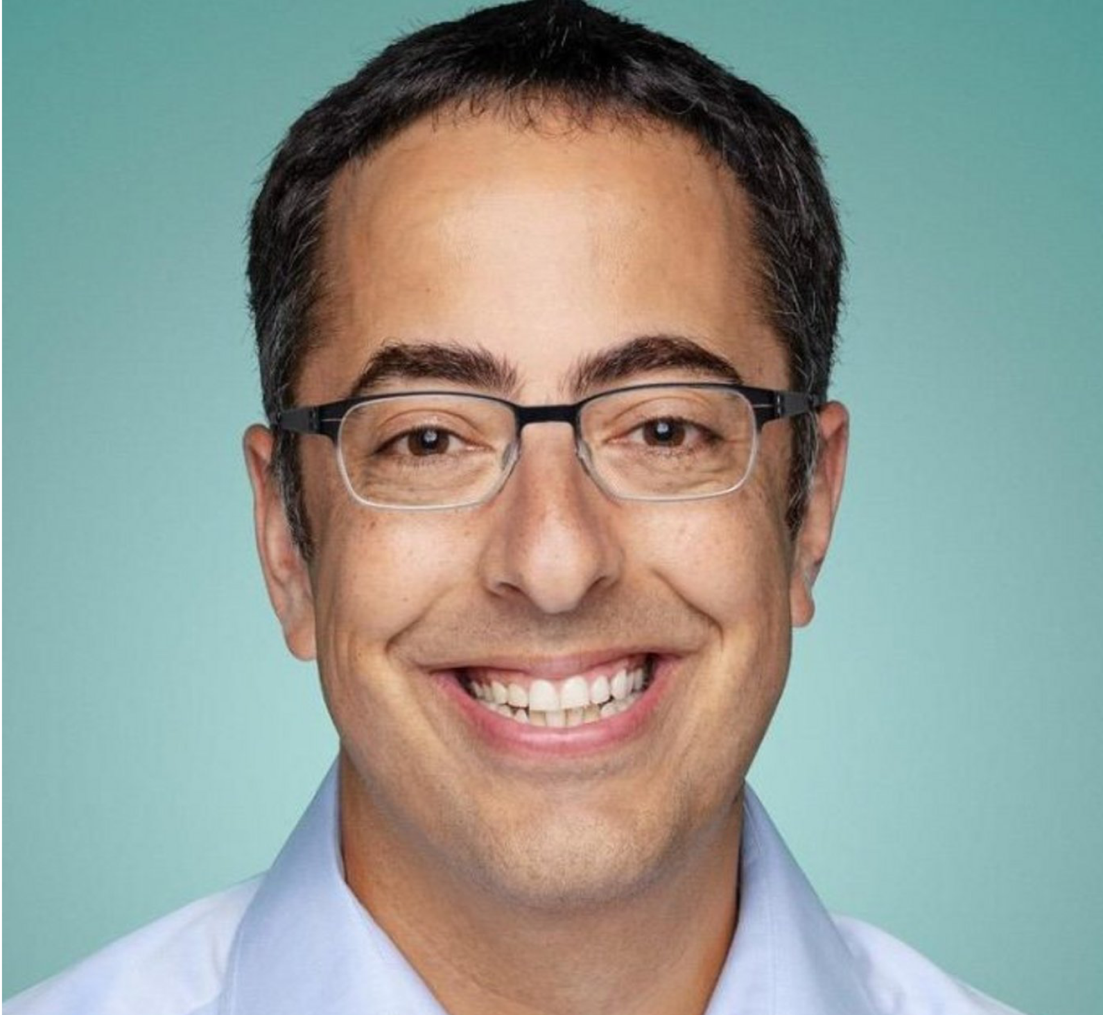 Photo of Lior Ron, event speaker; Headshot of a smiling man with short, dark hair and glasses, wearing a light-blue collared button-down shirt. The background is a solid, light teal color.