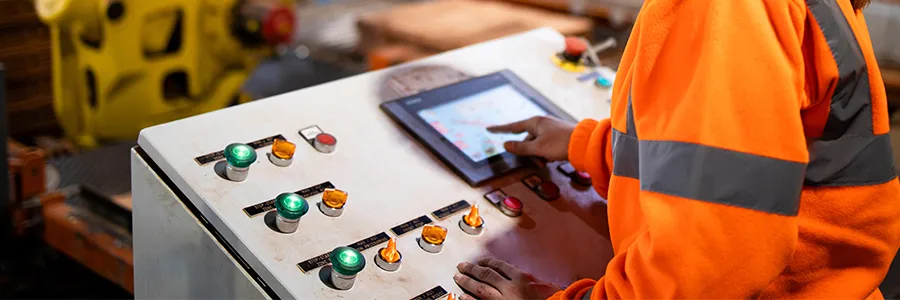 A worker in a manufacturing facility using an industrial touchscreen HMI